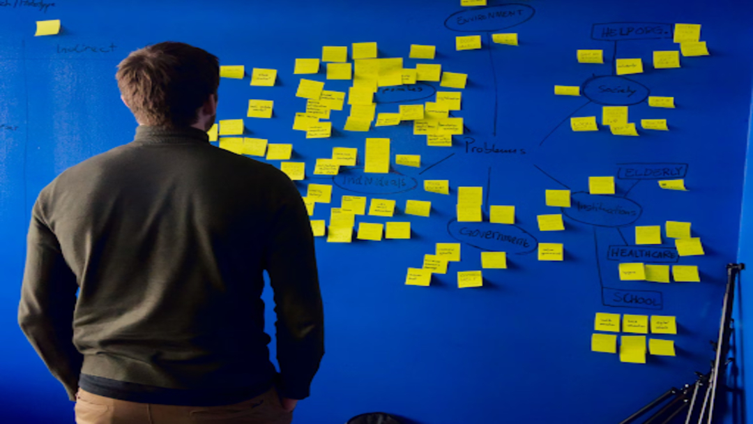 Man looking at a wall full of post-it notes