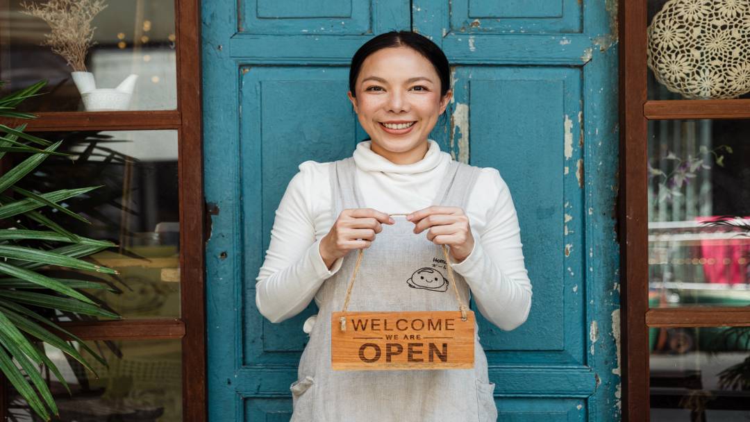 Woman holding an open sign in front of a door