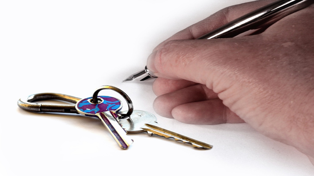 Pen signing paper next to house keys