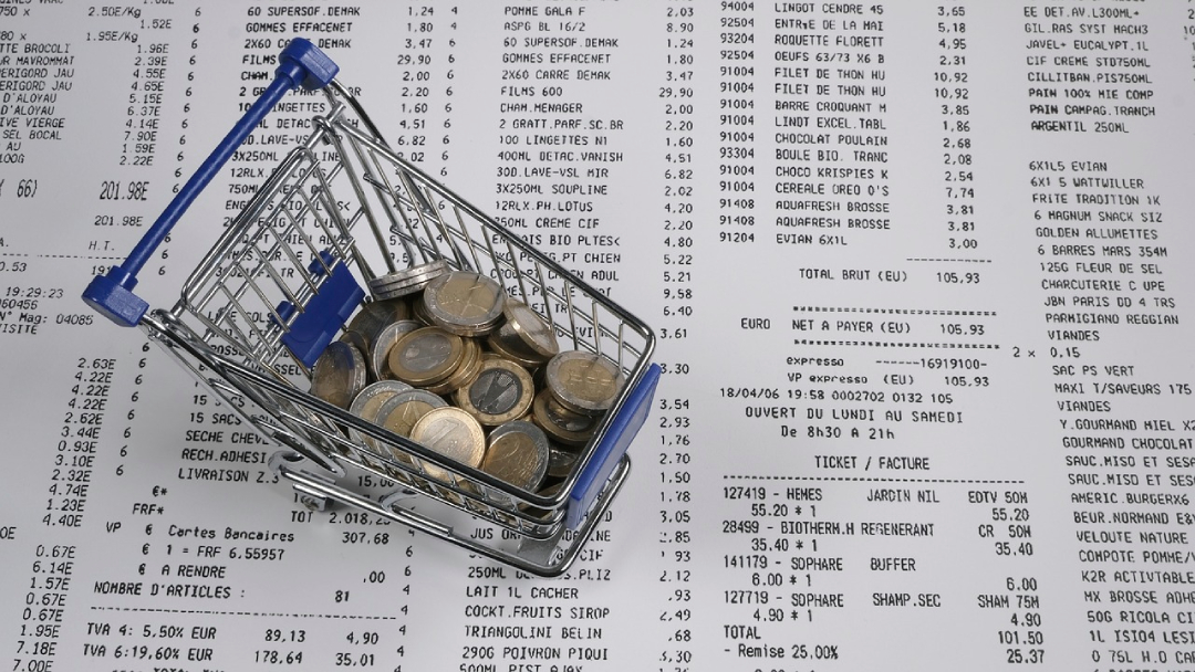 Shopping cart with coins next to a expenses