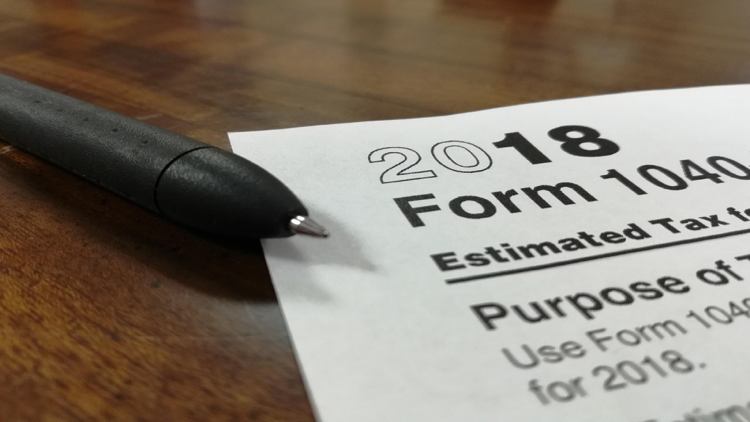 Someone reviewing their tax form with a black pen